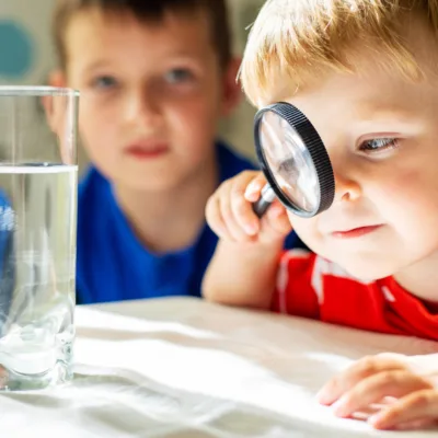 The child boy looking at water in a glass through magnifying glass